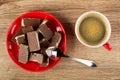 Pieces of chocolate with porous filling in saucer, spoon, cup with black coffee on table. Top view Royalty Free Stock Photo