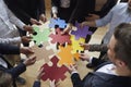 Pieces of colored puzzles in hands of people standing in circle and assembling them. Royalty Free Stock Photo