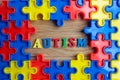 Pieces from a colorful jigsaw puzzle arranged to form a page on wooden background. Break barriers together for autism