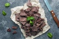 Pieces of crushed dark chocolate with mint leaves dark textured background. Close up Royalty Free Stock Photo