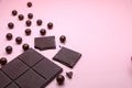 Pieces of dark chocolate bar and milk chocolate pearls on pink background, top view, copy space Royalty Free Stock Photo