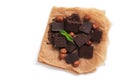 Pieces of dark chocolate, hazelnuts and mint on parchment paper, white background, isolated. View from above