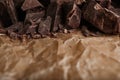Pieces of dark chocolate on parchment. Space for text Royalty Free Stock Photo