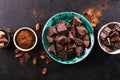 Pieces of dark chocolate in a vintage bowl, cocoa powder and cocoa beans on a dark textured background, top view. Royalty Free Stock Photo