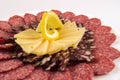 Pieces of dark and light sausage with hard cheese and lemon on a white plate Royalty Free Stock Photo