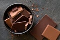 Pieces of dark and milk chocolate in black ceramic bowl isolated on grey slate from above. Small bits of chocolate Royalty Free Stock Photo