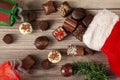 Pieces of delicious assorted chocolates are coming out of a christmas stocking on wooden table Royalty Free Stock Photo