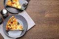 Pieces of delicious homemade salmon quiche with broccoli, fork and salt shaker on wooden table, flat lay. Space for text