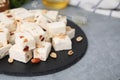 Pieces of delicious nutty nougat on grey table, closeup