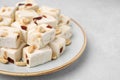 Pieces of delicious nutty nougat on light table, closeup