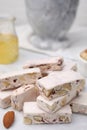 Pieces of delicious nutty nougat on white table, closeup