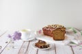 Pieces of delicious, sweet cupcake on white saucer, cup of tea, sprig of lilac on wooden background with linen napkin. Homemade