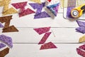 Pieces of fabric sewn in the shape of the letter Z, stacks of multi-colored pieces of fabric, pincushion, quilting accessories on