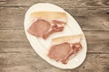 Pieces of fresh raw pork appetizing close-up on a white porcelain plate on a wooden background.