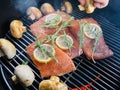 Pieces of a fresh salmon spread on a lattice round a grill for smoking, slices of a lemon and a branch of rosemary put