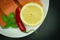 Pieces of Fresh Salmon top view white plate. isolated on black. Served with chilli pepper, lemon and greens Royalty Free Stock Photo