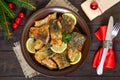 Pieces of fried fish carp on a ceramic plate on a dark wooden background Royalty Free Stock Photo