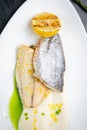 pieces of fried fish with sauce and fried lemon on a white plate top view Royalty Free Stock Photo
