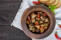 Pieces of fried pork with chilli in a clay bowl on a dark wooden background. Royalty Free Stock Photo