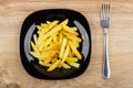 Pieces of fried potatoes in black plate and fork Royalty Free Stock Photo