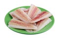 Pieces of frozen atlantic hake fish lying on a green plate isolated