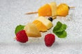 Pieces of fruit skewer on silver shiny background. Royalty Free Stock Photo