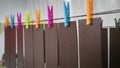 Pieces of genuine leather hanging on clothesline with colorful clothespins for drying after painting