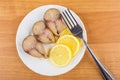 Pieces of mackerel, slices of lemon and fork in plate Royalty Free Stock Photo