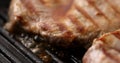 Pieces of meat are fried on a grill pan. Close-up dolly shot.