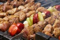 Pieces of meat are friend on fire on skewers on grill with veg. close up Royalty Free Stock Photo