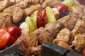 Pieces of meat are friend on fire on skewers on grill with veg. close up Royalty Free Stock Photo