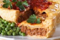 Pieces of meat pie and a garnish of green peas. Horizontal macro Royalty Free Stock Photo