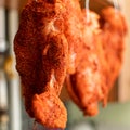 Pieces of meat in seasoning hang on hooks. Drying chicken meat, curing meat