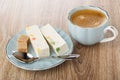 Pieces of nougat with marmalade, sugar, spoon on saucer, coffee in cup on table