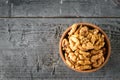 Pieces of peeled walnut in a wooden bowl on a dark wooden table. The view from the top