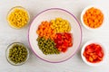 Pieces of pepper, carrot, green peas, corn in ceramic bowl and glass bowls with ingredients on table. Top view Royalty Free Stock Photo