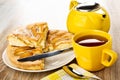 Pieces of pie with apples charlotte, knife in plate, teapot, cup with tea, spoon on napkin on table Royalty Free Stock Photo