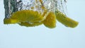 Pieces pineapple dropped water in super slow motion close up. Ananas floating.