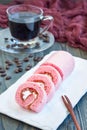 Pieces of pink swiss roll with strawberry jam and cream on a white plate, vertical