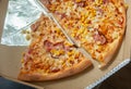 Pieces of pizza with bacon and corn in an open cardboard box