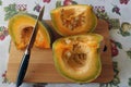 pieces of pumpkin with original yellow-green pulp on a wooden board are cut with a knife