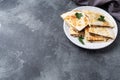 Pieces of quesadilla with mushrooms sour cream and cheese on a plate with parsley leaves. Concrete background copy space