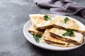 Pieces of quesadilla with mushrooms sour cream and cheese on a plate with parsley leaves. Concrete background copy space