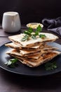 Pieces of quesadilla with mushrooms sour cream and cheese on a plate with parsley leaves. Wooden background close up