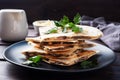 Pieces of quesadilla with mushrooms sour cream and cheese on a plate with parsley leaves. Wooden background close up