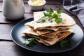 Pieces of quesadilla with mushrooms sour cream and cheese on a plate with parsley leaves. Wooden background close up.