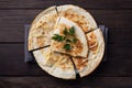 Pieces of quesadilla with mushrooms sour cream and cheese on a plate with parsley leaves. Wooden background copy space.