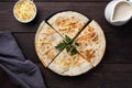 Pieces of quesadilla with mushrooms sour cream and cheese on a plate with parsley leaves. Wooden background copy space.