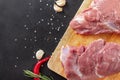 Pieces of raw meat on a kitchen Board with garlic  and red chili pepper on a black background, pork Royalty Free Stock Photo