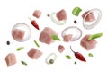 Pieces of raw pork and other ingredients for goulash flying on white background